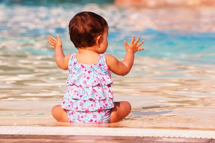 baby sitting at edge of pool