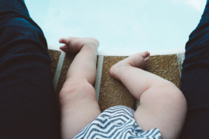 baby’s legs at edge of pool wearing white and gray stripes