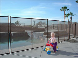 toddler on bike in front of pool fence