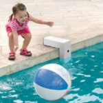 toddler next to pool alarm reaching for floating ball