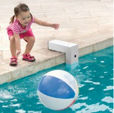 toddler next to pool alarm reaching for floating ball