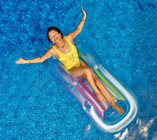 woman floating in pool on plastic lounge chair