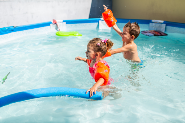 boy and girl splashing in pool with pool toys