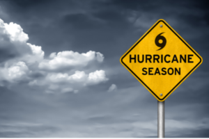 bright yellow road sign reading 'hurricane season' with a background of cloudy skies