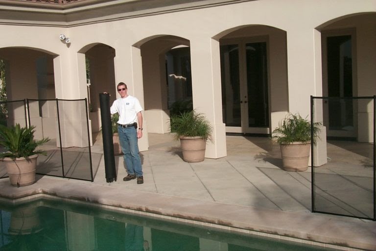 man standing beside a pool with a rolled up section of mesh pool fencing, displaying the ease of installation and removal of pool fencing