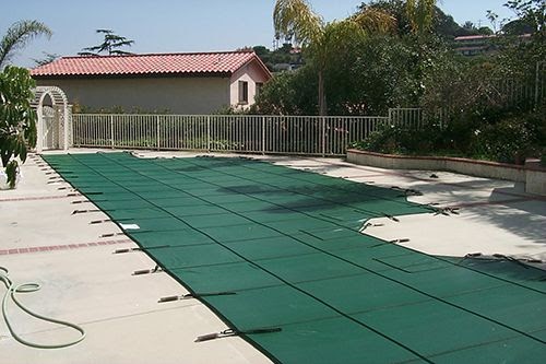 backyard pool with an installed mesh pool cover