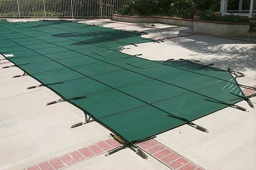 A green mesh winter pool cover installed on a swimming pool