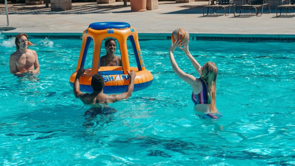 four adults playing a swimming pool floating game