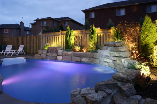 backyard pool with lighting features and waterfall