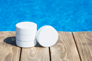 chlorine pool tablets stacked next to a swimming pool