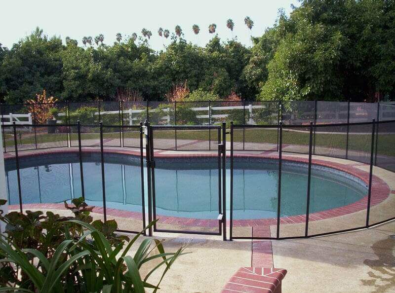 black mesh pool safety fence installed around a backyard pool
