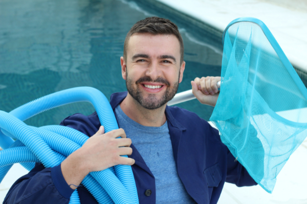 man in a blue shirt holding a pool pump and pool net
