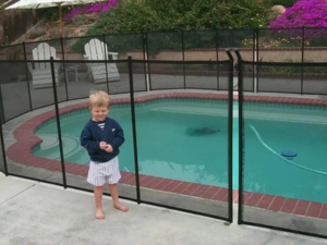 toddler standing in front of an installed pool safety fence