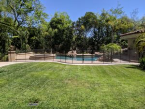Black mesh pool fence installed in a residential backyard