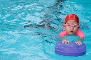 child learning how to swim with swimming equipment