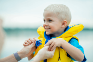 Child being fastened into a life vest
