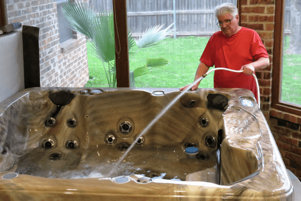 elderly man cleaning his empty hot tub