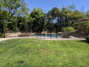 Mesh removable pool fence installed on a backyard pool