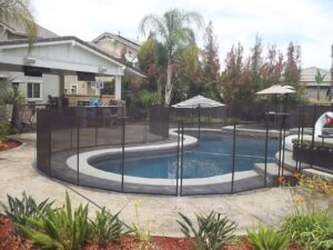 Black mesh removable pool fence installed around a residential swimming pool