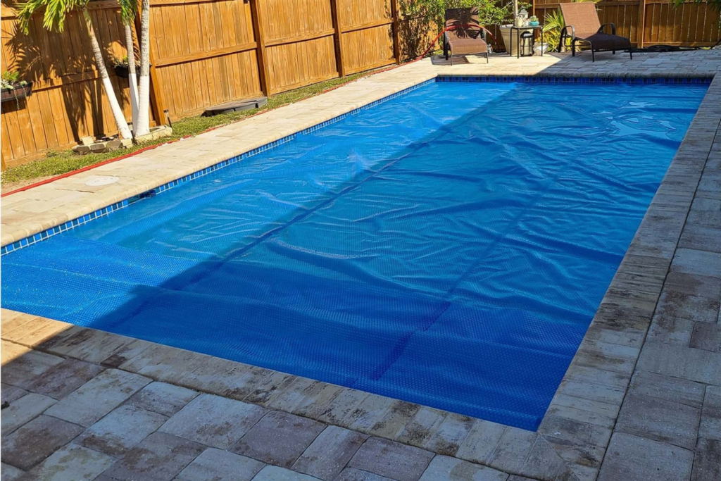 Blue evaporation cover installed on a backyard swimming pool