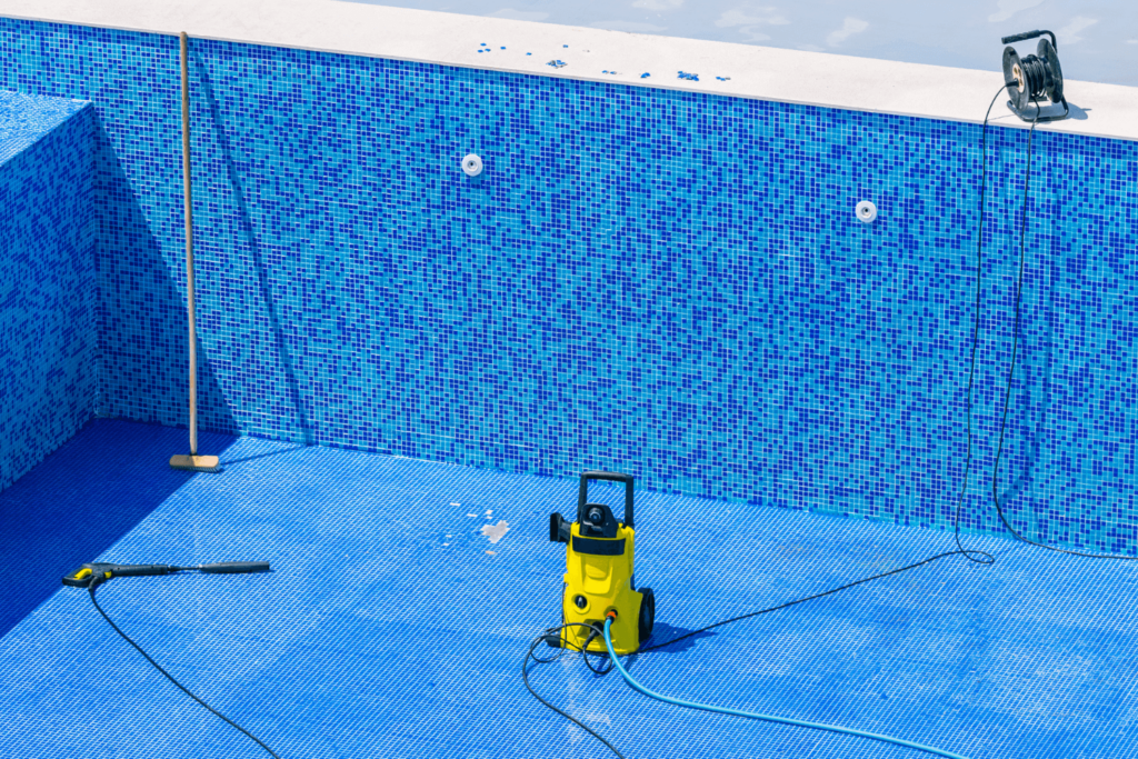Empty swimming pool with cleaning tools sitting at the bottom
