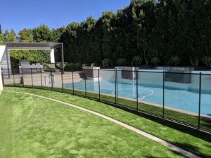 Black mesh removable pool fence installed around a rectangular swimming pool