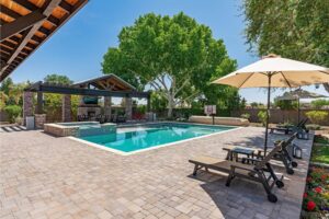 Beautiful residential backyard showing a large swimming pool and a brick pool deck