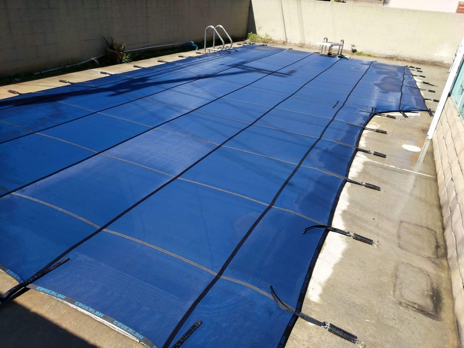 blue mesh pool cover installed over a small swimming pool