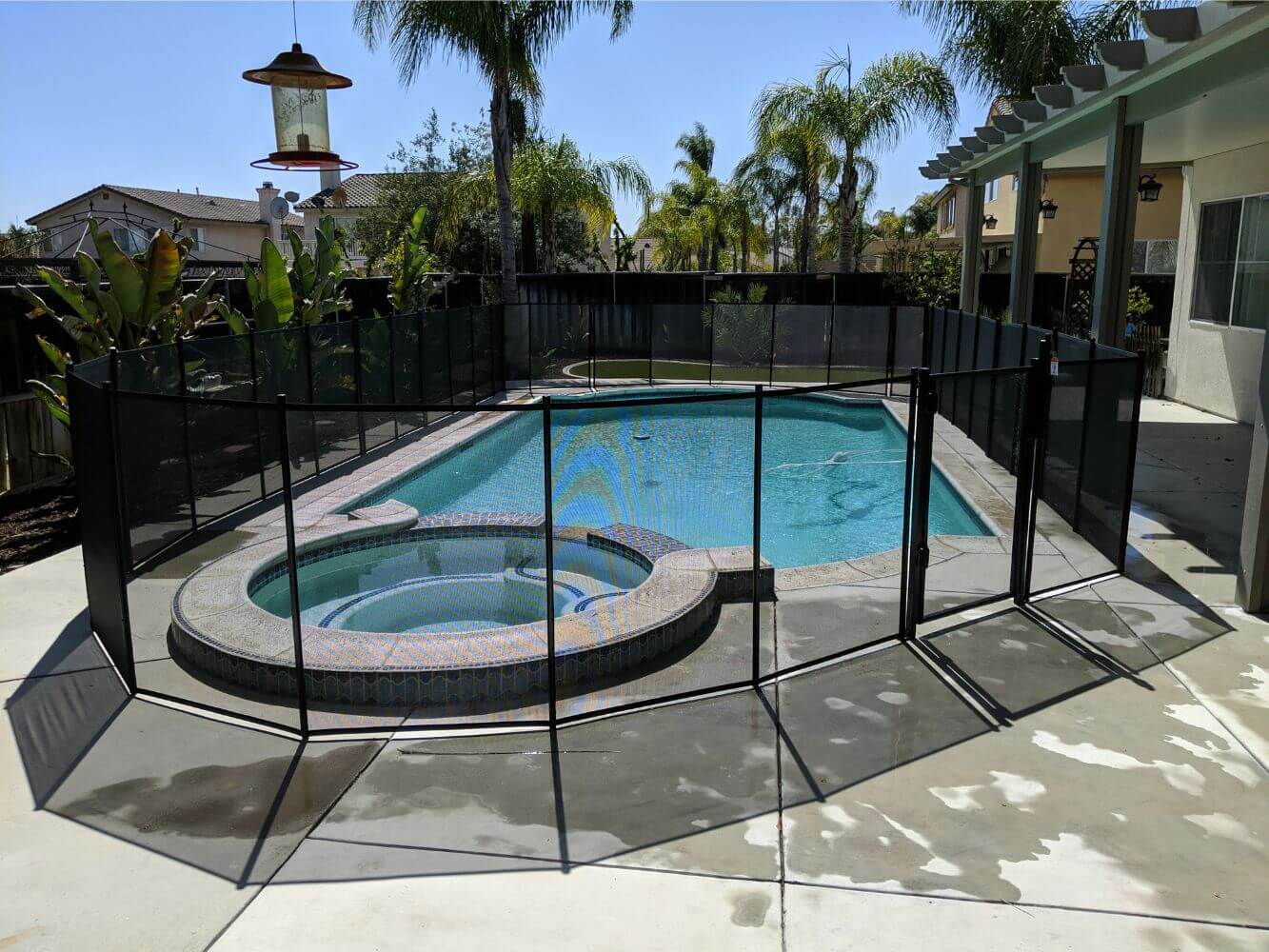 Black mesh swimming pool fence installed around a residential swimming pool
