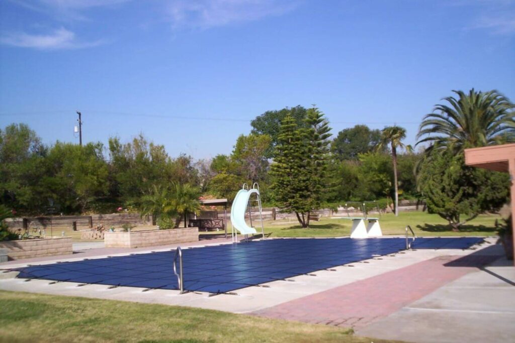 blue mesh winter pool cover secured on a backyard swimming pool