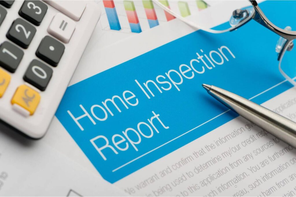 A home inspection report with a calculator and pen placed over it