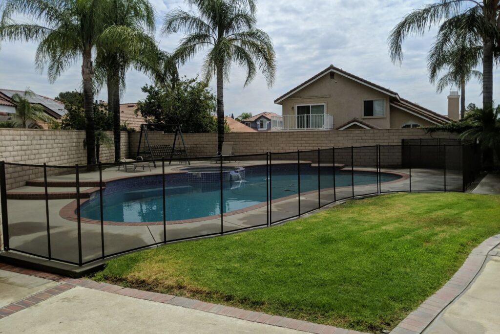 Small backyard with a swimming pool that has a safety fence installed surrounding it