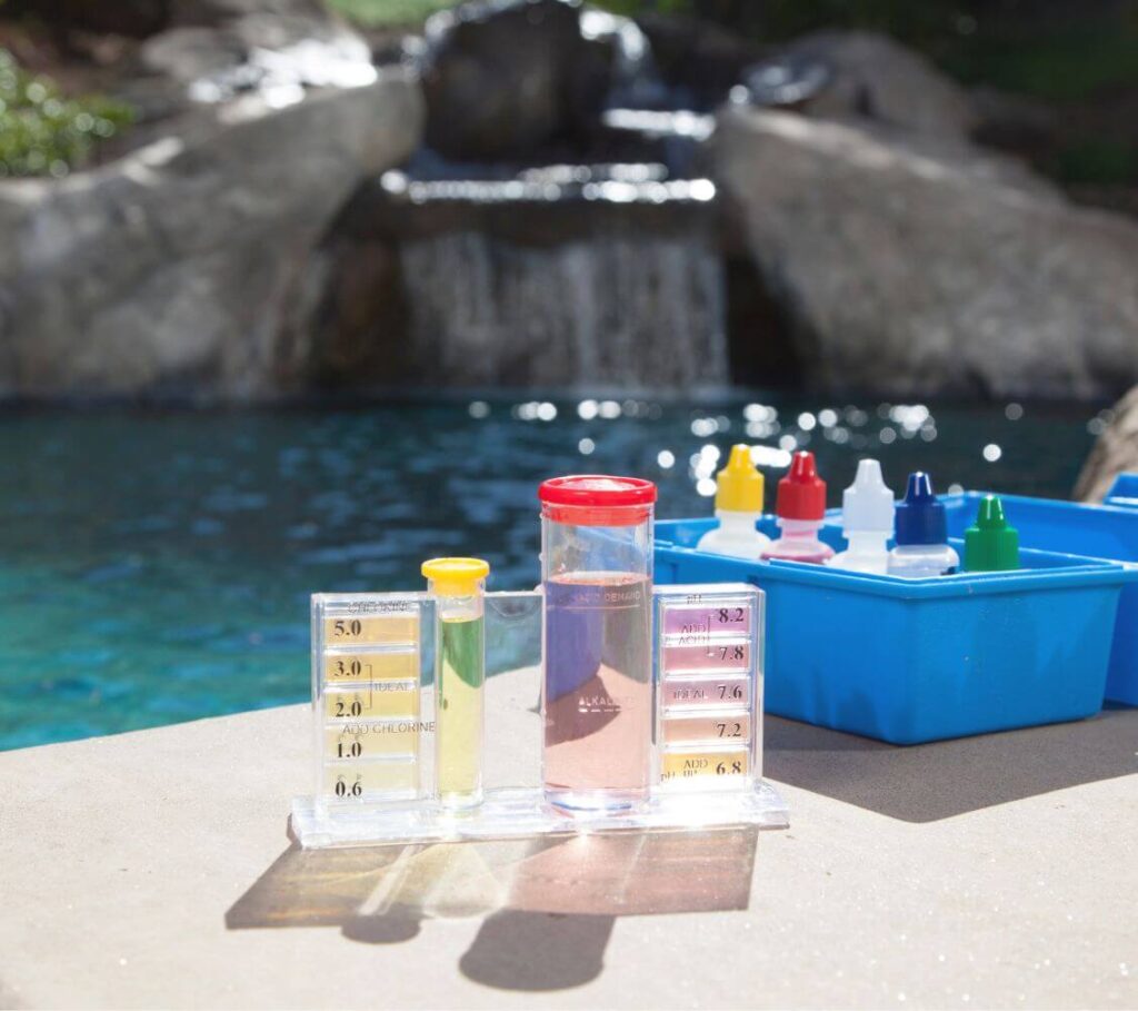 pool cleaning chemicals sitting next to a swimming pool with a waterfall feature