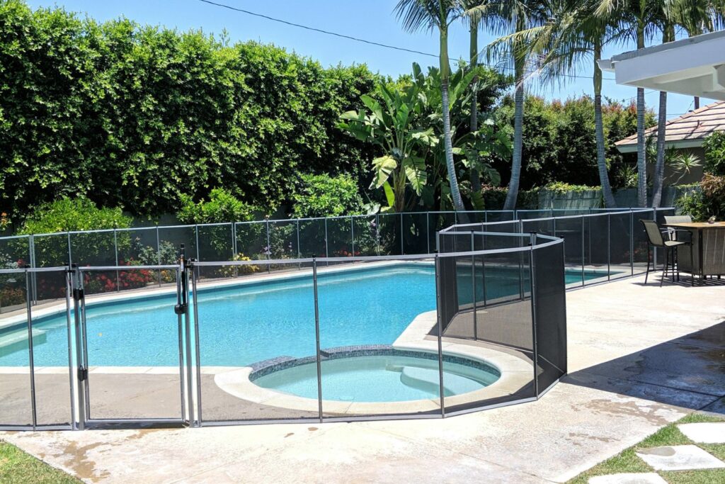 Backyard pool with mesh safety fence around it.