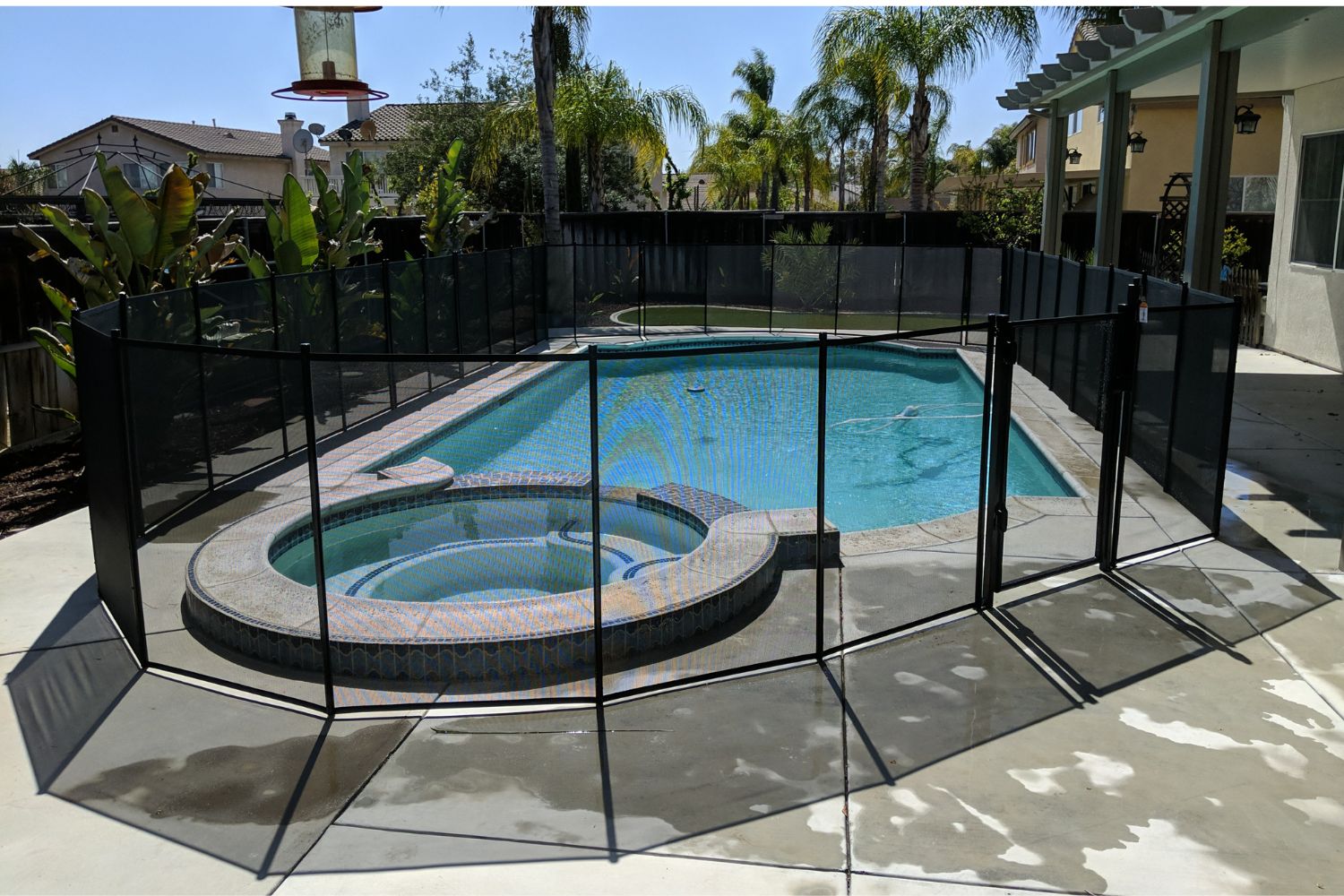 Black mesh pool fence around backyard pool