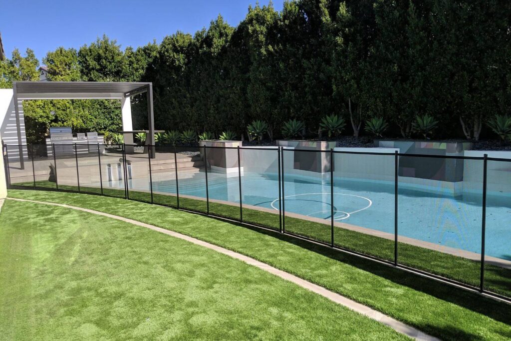 Black mesh pool safety fence surrounding a backyard swimming pool