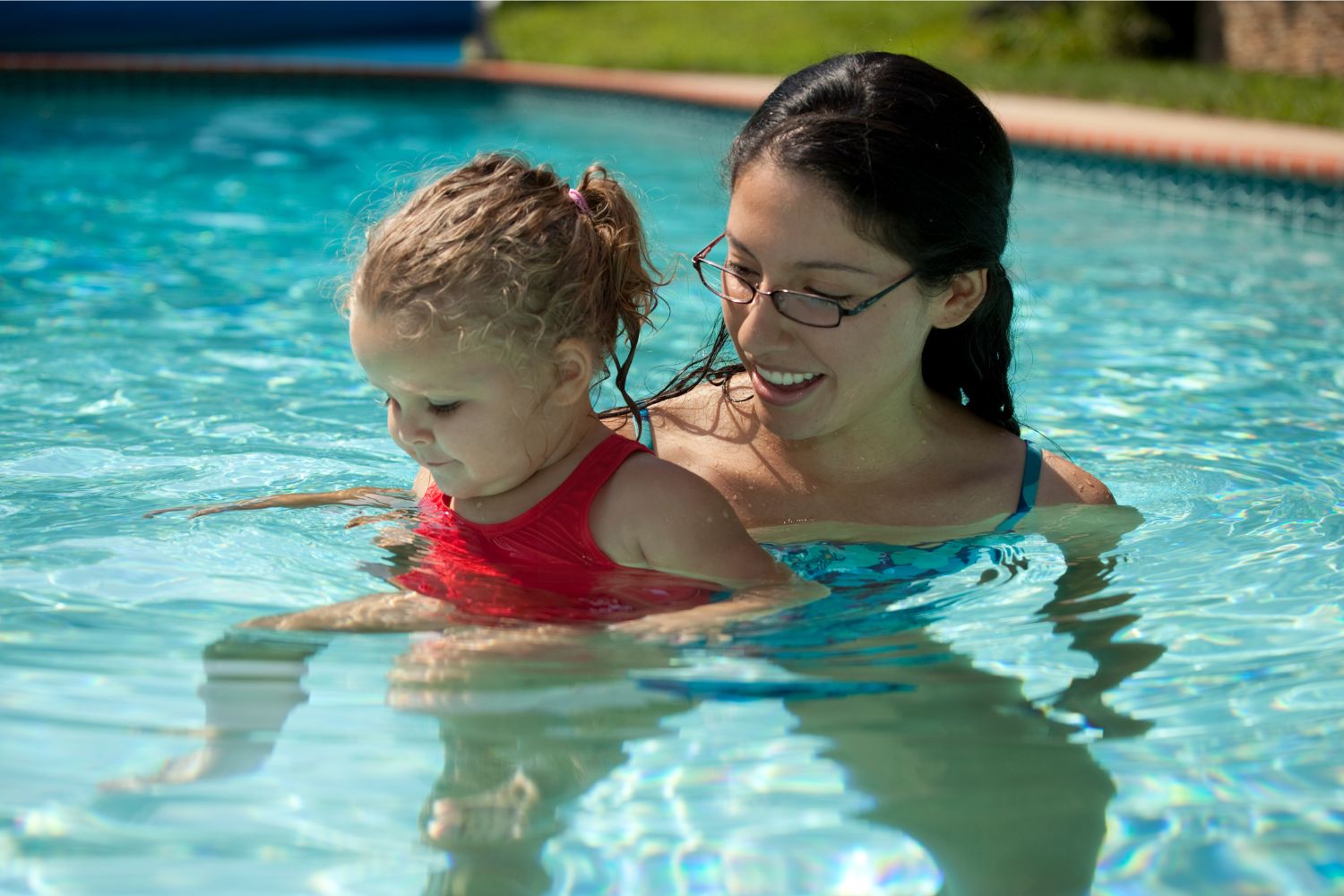 young woman in pool holding infant