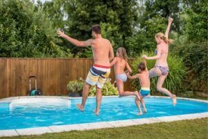 A family of four holding hands as they jump into a swimming pool