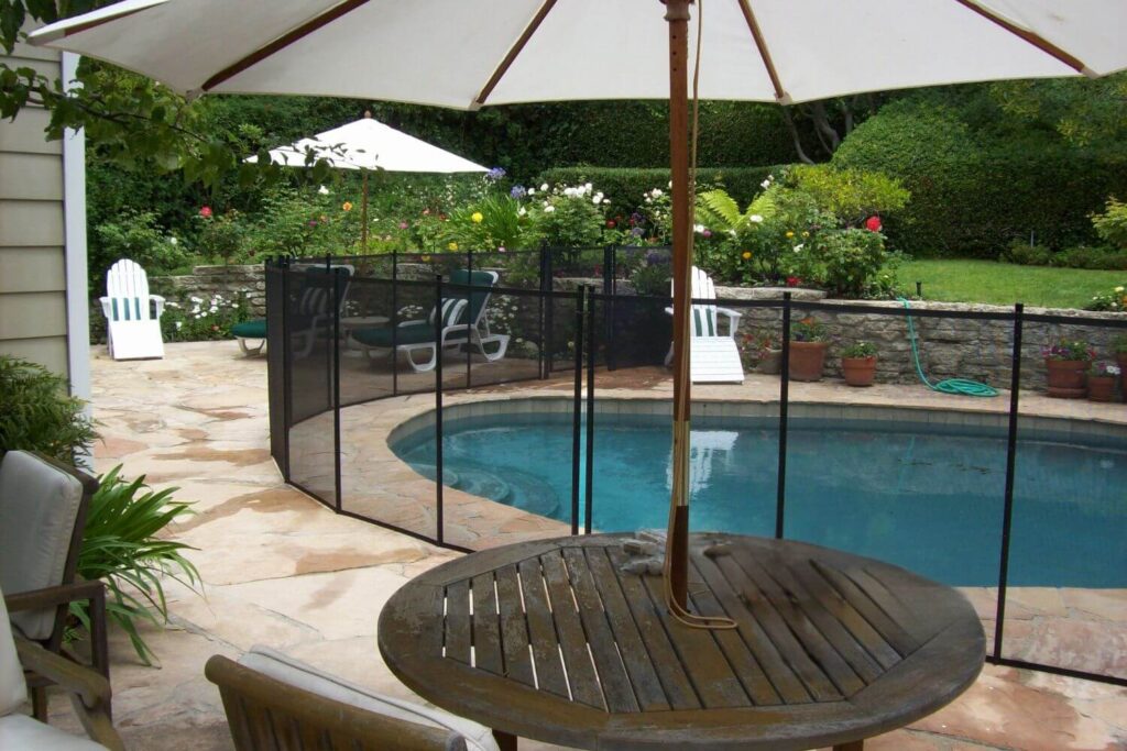 Black mesh removable pool fence installed around a swimming pool