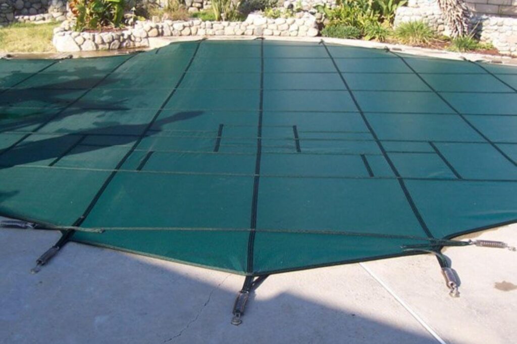 Green mesh winter pool cover installed over a swimming pool
