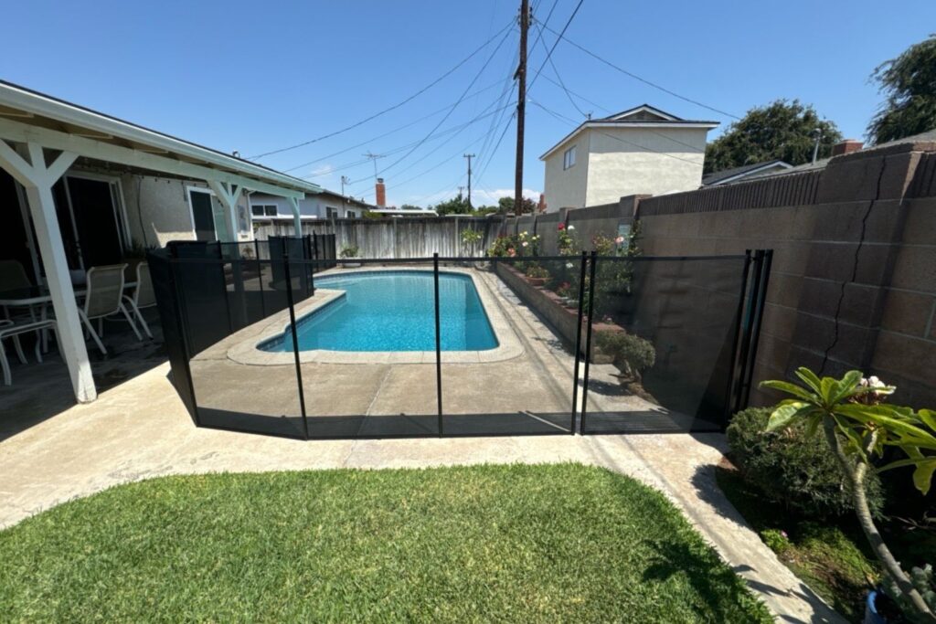 black mesh pool fence installed around a backyard pool