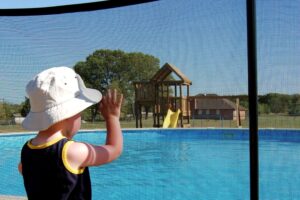 Small child standing outside a mesh pool fence