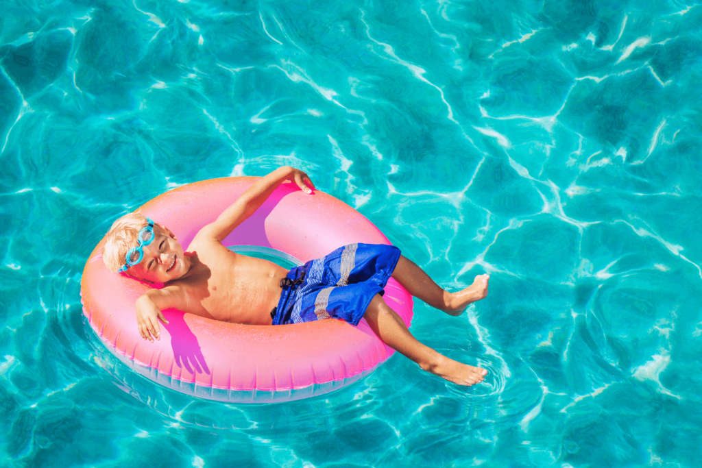 boy floating in a swimming pool on a pink circular float