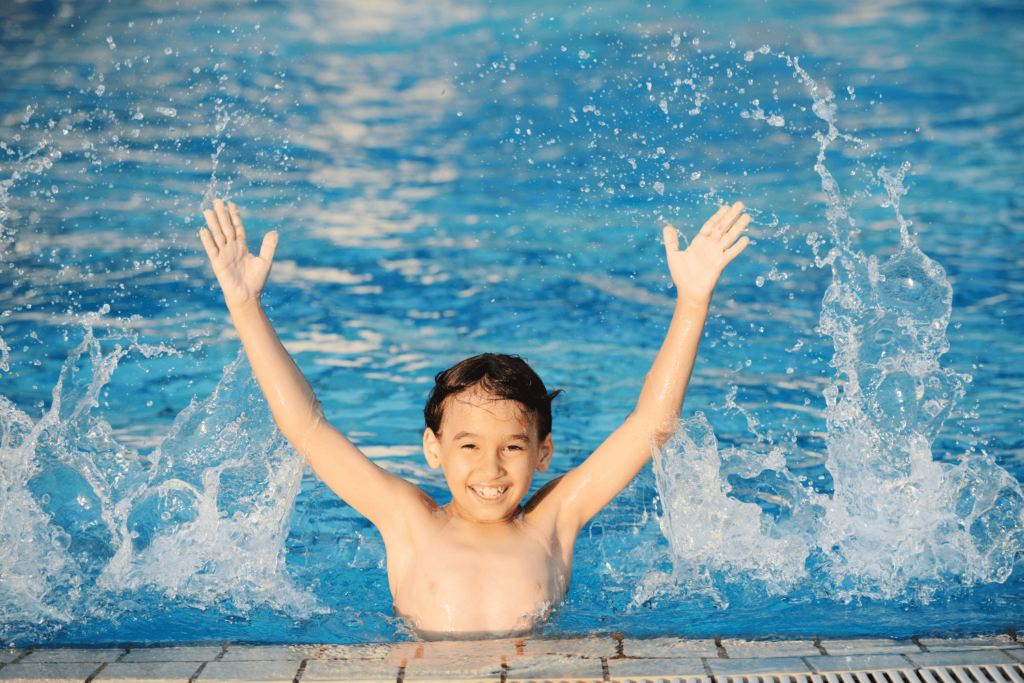 Young child in a swimming pool splashing water.