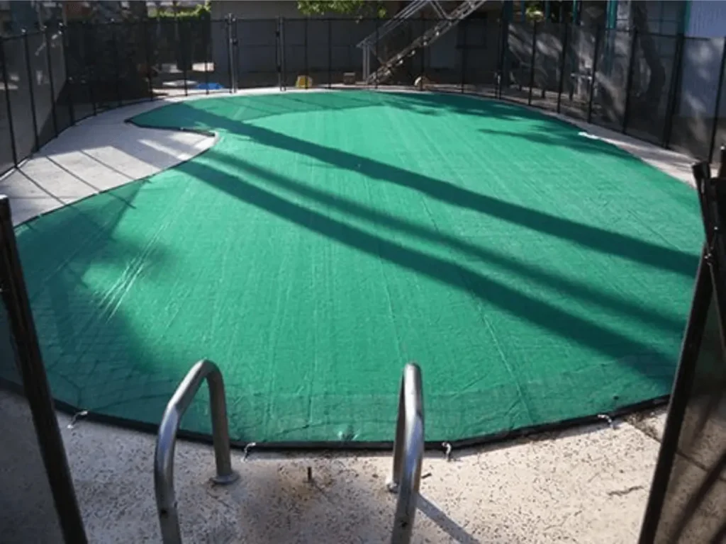 Green pool leaf cover installed over an irregular shaped swimming pool