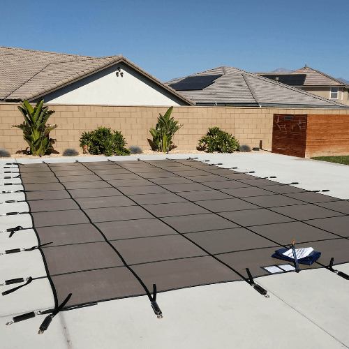 Black pool safety cover installed on a rectangular pool