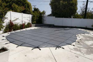 Black mesh swimming pool safety cover installed on a swimming pool