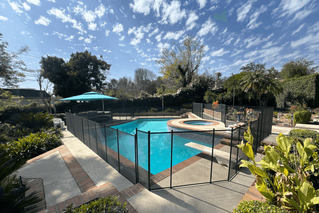 Black mesh removable pool fence installed around a backyard swimming pool