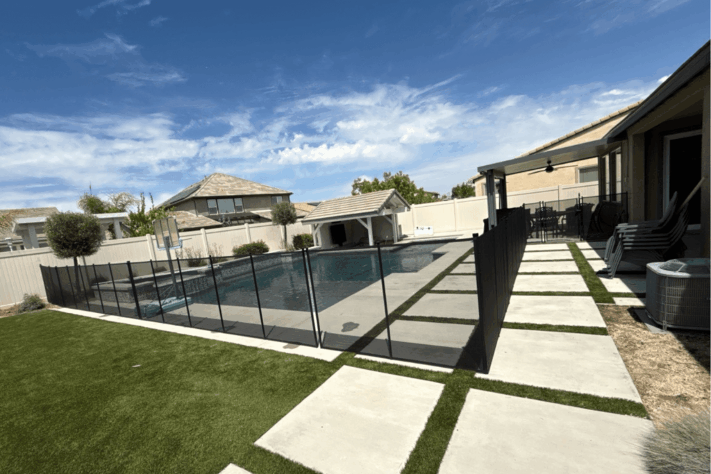 black mesh pool fence installed around a large backyard swimming pool
