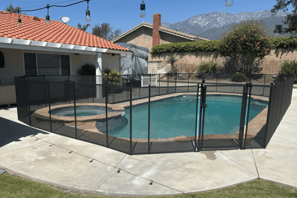 black mesh pool fence installed around a small backyard swimming pool